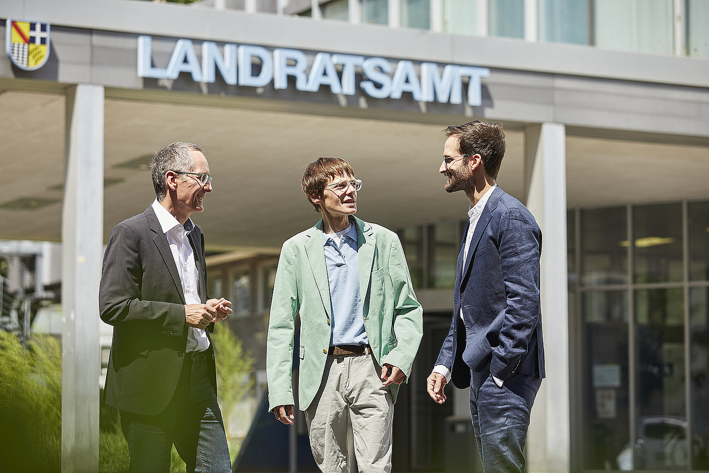 Drei Männer stehen vor dem Landratsamt und unterhalten sich